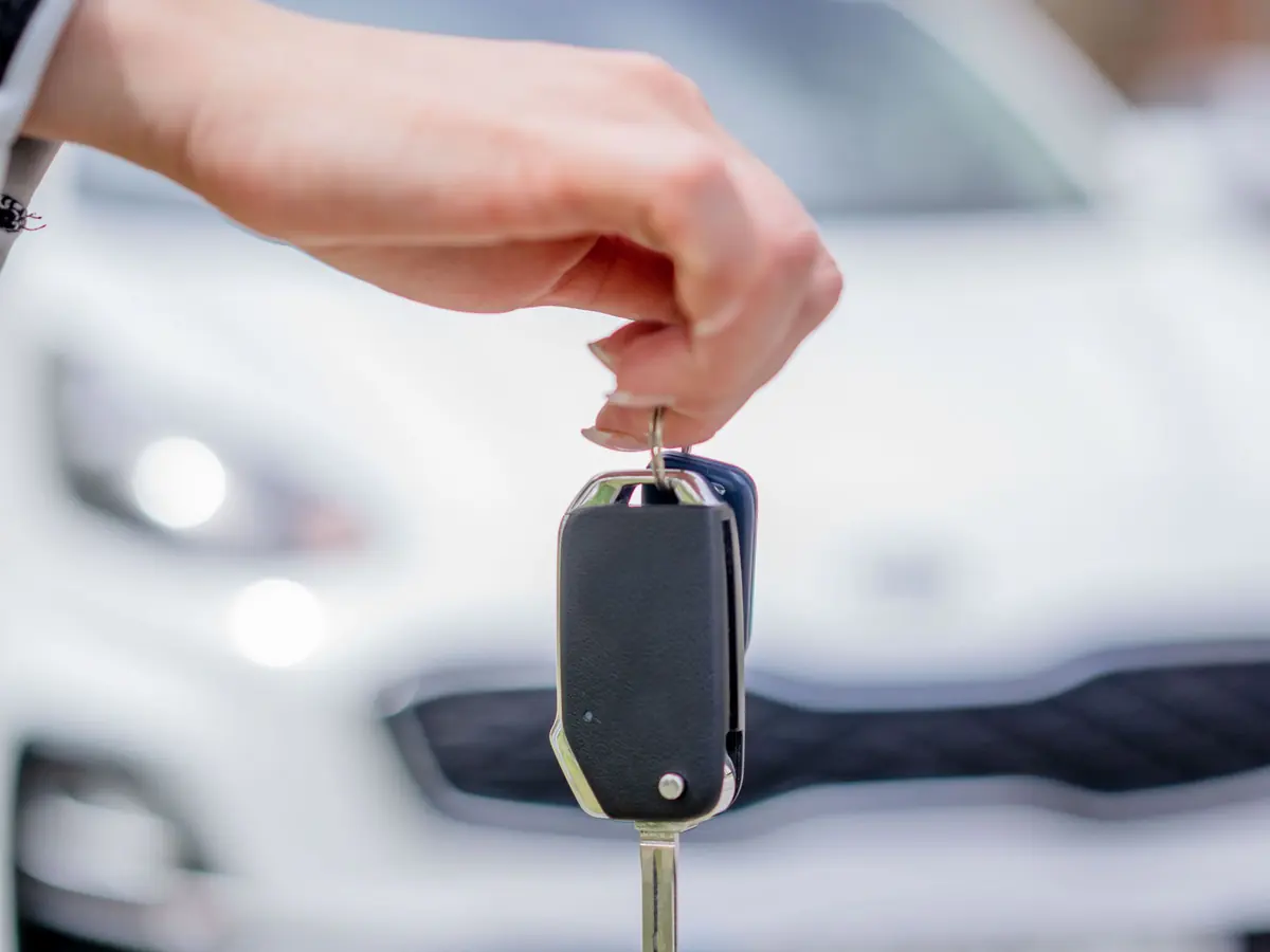 Car keys handed over in front of a white car