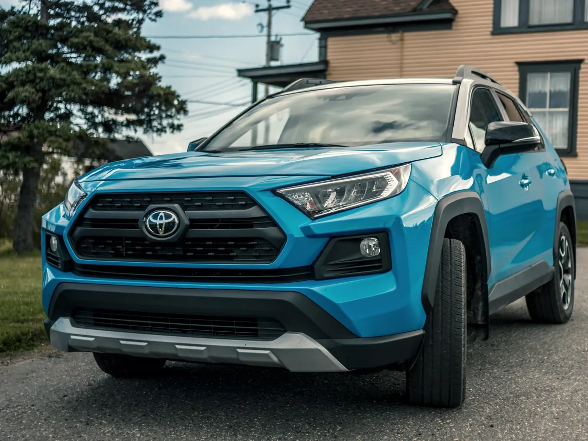 Blue Toyota RAV4 SUV parked by a house
